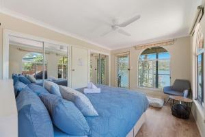 un grand lit bleu dans une pièce avec des fenêtres dans l'établissement Dorathee Cottage - Pet Friendly - Absolute Waterfront, à Gunderman
