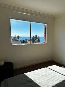 een slaapkamer met een raam met uitzicht op de oceaan bij Beach & Ocean View Apartments Tamarama in Sydney