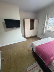 una camera da letto con un letto e una TV a schermo piatto di Casa rosa - conforto com split, wifi e água quente a Belém