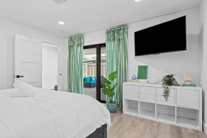 ポンパノビーチにあるWaterfront Villaの白いベッドルーム(大型ベッド1台、薄型テレビ付)