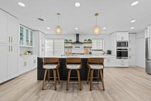ポンパノビーチにあるWaterfront Villaの白いキャビネットとバースツールを備えたキッチン