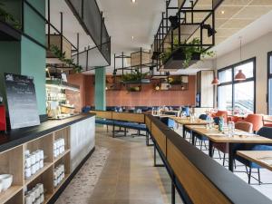 Un comedor con mesas y sillas y ventanas. en ibis Lyon Sud Oullins, en Oullins