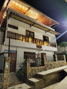 a white house with a balcony and a stone wall at Yaku Wasi in Leimebamba