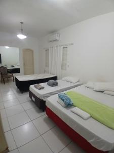 een kamer met drie bedden en een stoel erin bij Áurea da Mata in Cuiabá