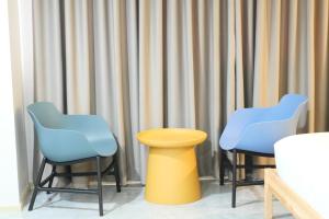 two blue chairs and a yellow stool in a room at Chill Chill Hotel in Krabi