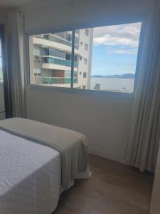 een slaapkamer met een bed en een groot raam bij Standard High Apartment in São José +15 foto's