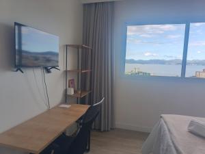 een kamer met een bureau en een groot raam bij Standard High Apartment in São José