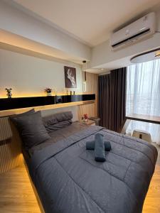 Schlafzimmer mit einem großen Bett mit blauer Decke in der Unterkunft Modern Luxury Studio at Pollux by Superstay in Batam Center