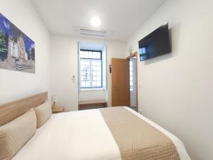a bedroom with a bed and a television on the wall at Misericórdia Rooms in Guarda