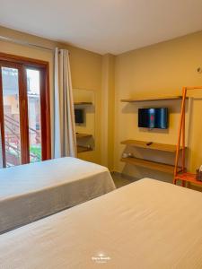 a room with two beds and a tv on the wall at Zaya Beach Residence in Icaraí +32 photos