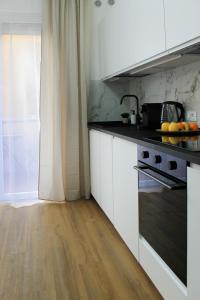 une cuisine avec des armoires blanches et des comptoirs noirs dans l'établissement Golden Nest Padova, à Padoue