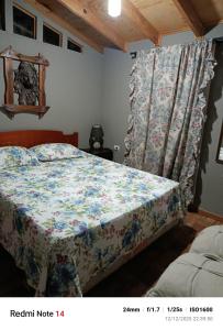 um quarto com uma cama com um edredão floral em La Morada del Colibrí em El Tabo
