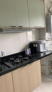 a kitchen counter with a stove and a microwave at Apartamento campinas lado Puc 2 in Campinas