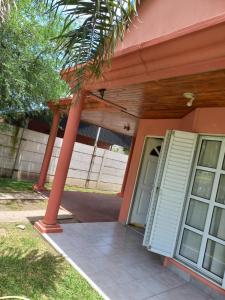 a front porch of a house with a palm tree at Alquiler Villa Elisa in Villa Elisa