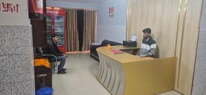 Zwei Männer sitzen an einer Theke in einem Büro. in der Unterkunft Atithi Guest House in Pūrnia