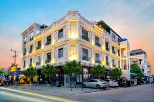 a white building with cars parked in front of it at Cambana Poipet Hotel in Krong Poi Pet