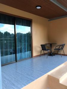 een patio met 2 stoelen, een tafel en ramen bij The Sun homestay in Ko Kood +3 foto's