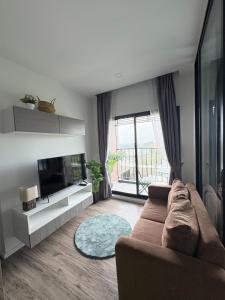 The Sriracha Perch في Ban Fang Daeng: غرفة معيشة مع أريكة وتلفزيون