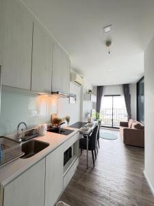 The Sriracha Perch في Ban Fang Daeng: مطبخ وغرفة معيشة مع طاولة وأريكة