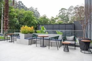 un patio esterno con tavoli, sedie e alberi di Bexpspces Sky Design Alphaville a Aldeia