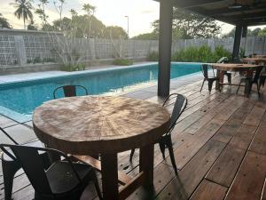 a wooden table and chairs next to a swimming pool at Sena Hotel Langkawi in Kampung Padang Masirat