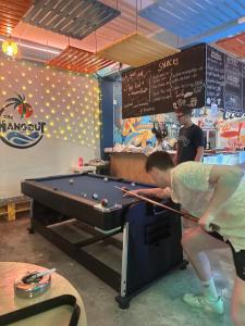 a man playing a game of pool in a store at The Hangout Hostel Ao Nang in Ao Nang Beach