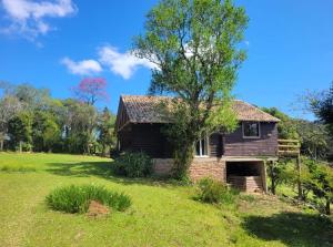 een oud huis in een veld met een boom bij Cabana do Lago- Morro da Borússia in Osório