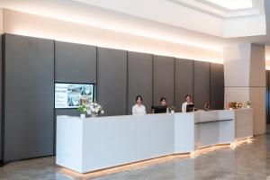 three people sitting at a reception desk in a lobby at lee hotel lat phrao in Bangkok