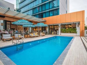 a pool with chairs and umbrellas in front of a building at The Adnate Perth - Art Series in Perth