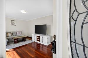 een woonkamer met een tv en een bank bij Spacious 4-Bed House with Private Garage in Coodanup