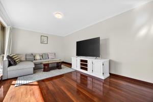 een woonkamer met een bank en een flatscreen-tv bij Spacious 4-Bed House with Private Garage in Coodanup