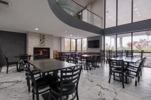 a dining room with tables and chairs and a fireplace at Baymont by Wyndham Louisville Airport South in Louisville