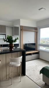 a kitchen with a counter and a chair and a table at Apartamento Novo in Capão da Canoa