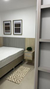 a bedroom with a bed and a table with a plant at Apartamento Novo in Capão da Canoa