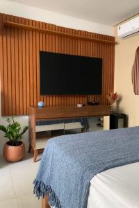 a bedroom with a flat screen tv on a wooden wall at Estúdio a 1 min do mar - Mila rooftop in Tamandaré