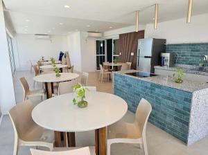 a restaurant with white tables and chairs and a kitchen at Estúdio a 1 min do mar - Mila rooftop in Tamandaré