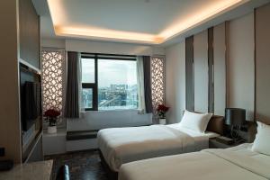 a hotel room with two beds and a window at lee hotel lat phrao in Bangkok