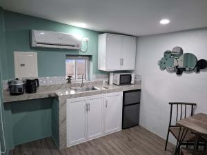 a kitchen with white cabinets and a sink and a table at Hidden Palms Inn Garden Deluxe in San Juan