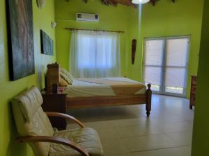 ein Schlafzimmer mit grünen Wänden, einem Bett und einem Stuhl in der Unterkunft A Serene Get Away in Vieux Fort