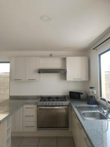 cocina con armarios blancos, fogones y fregadero en House A in a residential condominium with a pool, en Miranda 13 fotos más