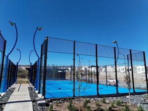 Una cancha de tenis detrás de una valla con luces. en House A in a residential condominium with a pool, en Miranda