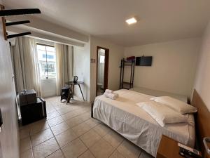 a bedroom with a bed and a television in it at Suites Centro Torres in Torres
