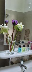 シギリヤにあるThe Cozy Nest - Sigiriyaのシンクの上に紫と白の花が入ったガラスの花瓶 +21枚の写真