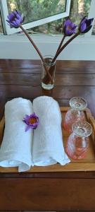 シギリヤにあるThe Cozy Nest - Sigiriyaのナプキンと紫色の花が入った花瓶が置かれたテーブル
