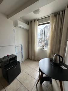 a living room with a table and a window at Suites Centro Torres in Torres
