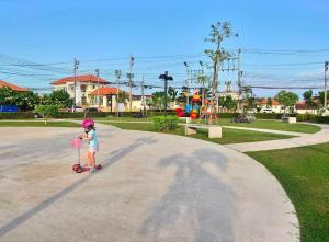 een klein meisje dat op een step door een park rijdt bij Holiday home in Ban Na Khua +3 foto's