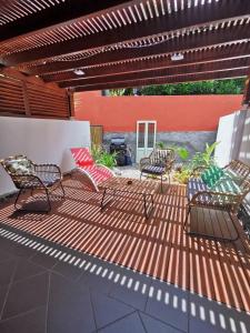 COTTAGE BLUE classé 3 étoiles - 4 à 6 personnes - 2 chambres - accès direct à la plage et à l'esplanade de Boucan Canot avec ses bars et restaurants في سان جيل لي بان: فناء مع كرسيين ومقعد على سطح السفينة +9 صور