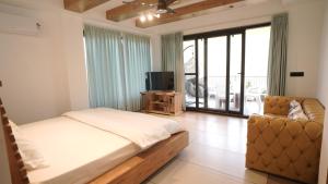 een slaapkamer met een bed, een bank en een televisie bij Amber Moon in Dagshai