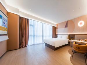 ein Hotelzimmer mit einem Bett und einem großen Fenster in der Unterkunft Orange Hotel Suzhou Shishan Financial Innovation Center in Suzhou