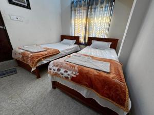 two twin beds in a room with a window at Hotel City Nibash in Dhaka